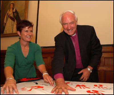 From right:  the
Assistant Anglican Bishop of Auckland, Richard Randerson,
pledges his support with a hand print, while Every Child
Counts Project Manager Deborah Morris-Travers, looks on.
