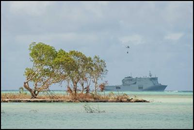 The HMNZS
CANTERBURY off the west coast of Niuatoputapu, with her
embarked Seasprite carrying an underslung load of relief
supplies to the island. 