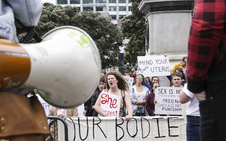 Protesters at
Parliament, showing a megaphone. Signs include: She
decides!; Mind you own uterus
