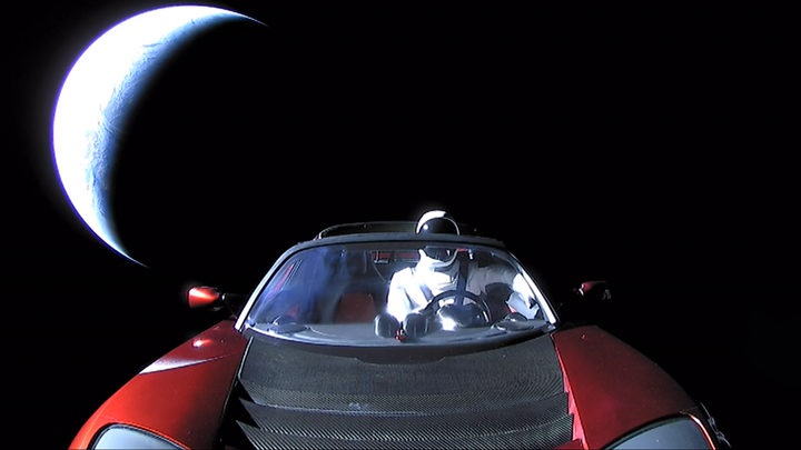 an open convertible
car in space, with a space suit in the driver's seat