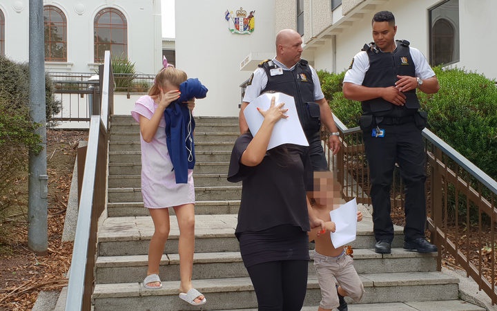 woman and two
children leaving court, with faces covered