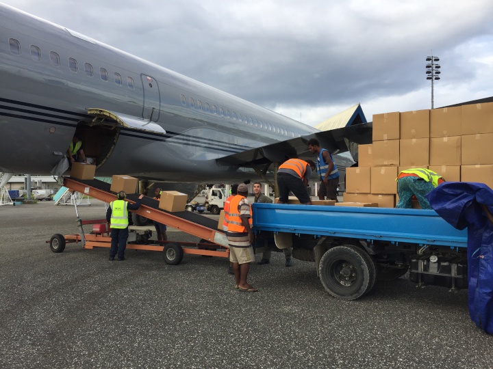 people loading
cardboard boxes from an airplane to a flatbed truck