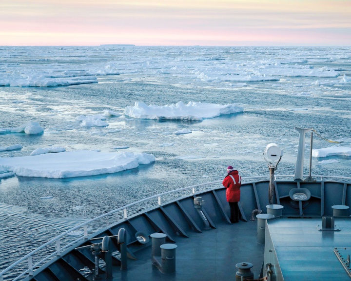a person on the
deck of a boat with floating chunks of sea ice around it