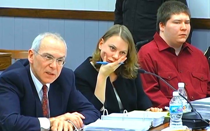 three people
sitting at a desk in court