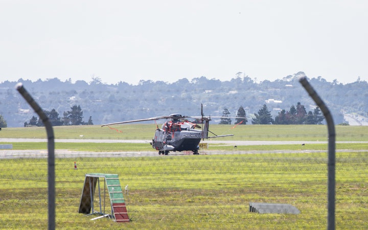 a helicopter
sitting on an airfield, seen through a wire fence