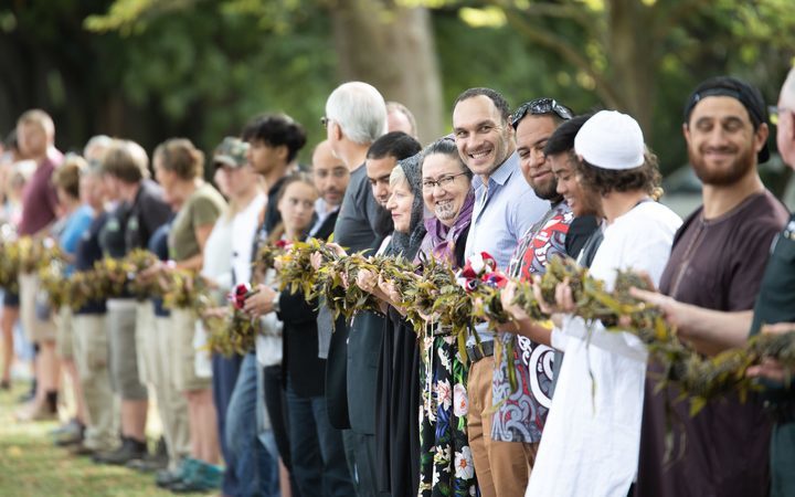 a line of people
holding up a woven-leaf lei