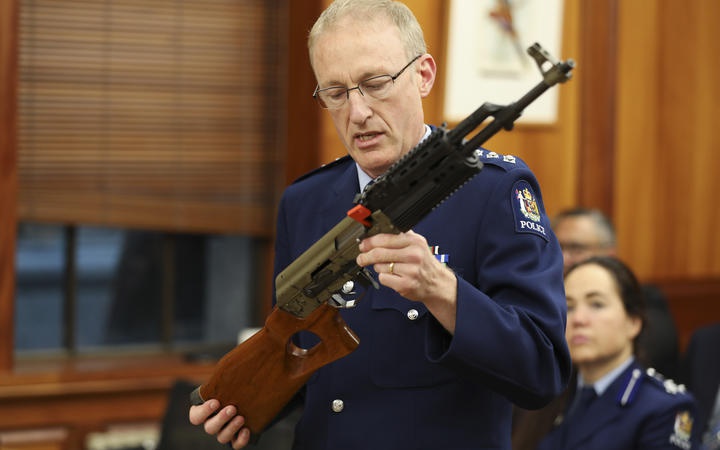 a police officer
showing features of a gun in a select committee room