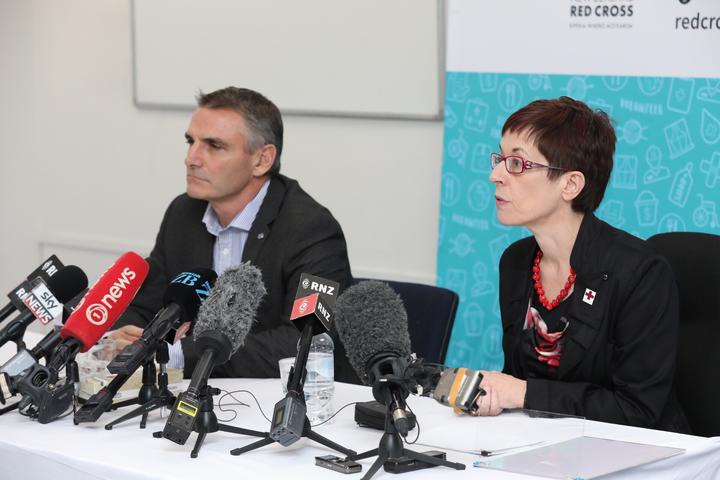 two people sitting
at a table with press conference microphones
