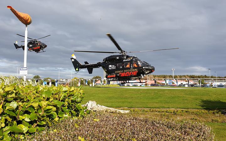 two helicopters,
low over a grassed landing field