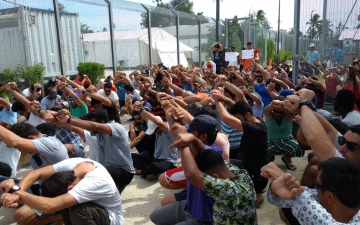 many detainees,
crouching with their arms crossed in the air