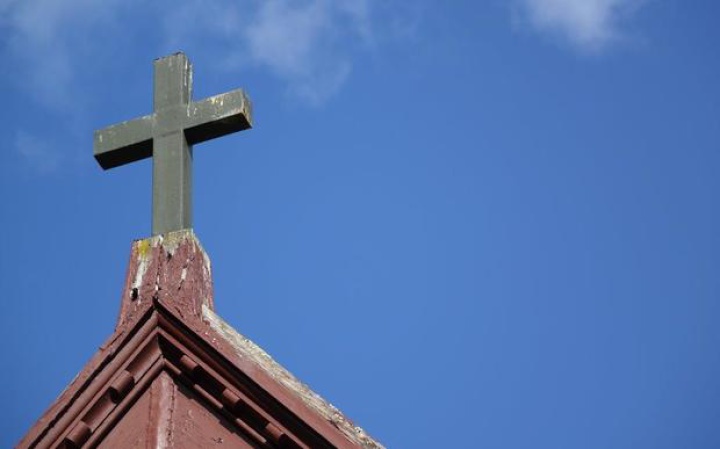 a church roof with
a cross on the peak, clear sky