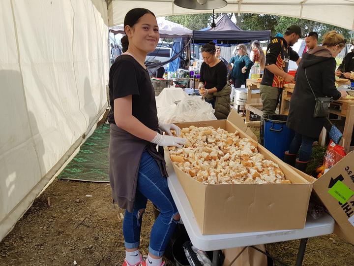 a young woman
beside a large cardboard catering box of what seems to be
shredded bread