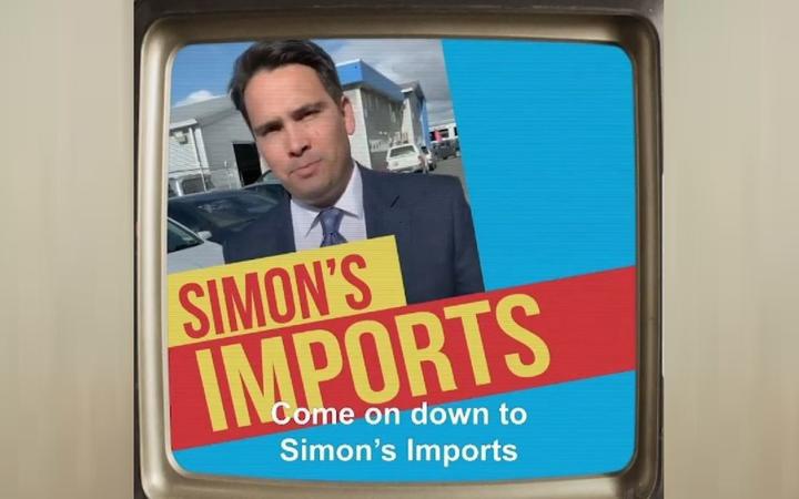 a picture of a tv
screen showing a picture of simon bridges and a banner
reading 'simon's imports'. Subtitled 'Come on down to
Simon's imports'