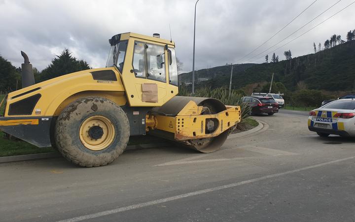 A road roller
stopped at the side of a road, with a police car nearby