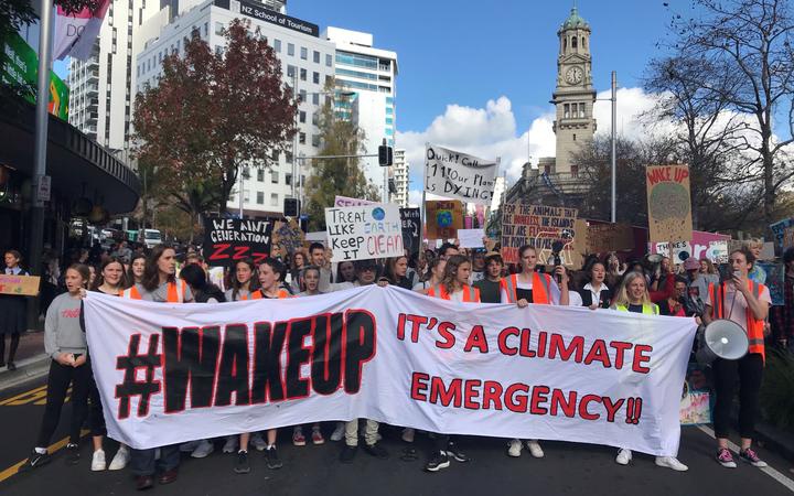 a crowd of young
protestors in the street led by a banner saying '#wakeup
it's a climate emergency' 