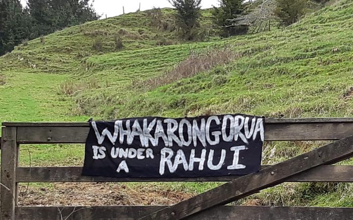 wooden fence at the
base of a slope, with a banner on it reading WHAKARONGRUA IS
UNDER A RAHUI