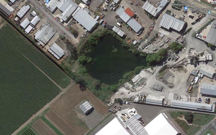 view from above of
a lake surrounded by plants in the between industrial and
farm land