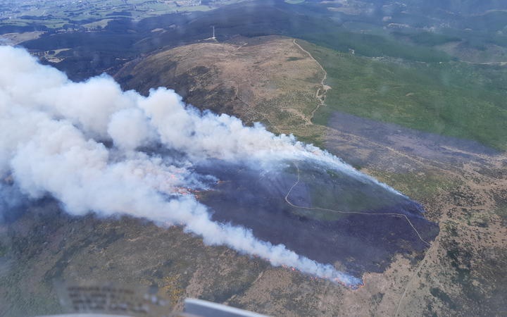 the fire viewed
from above: some rising from the edge of a large burned area
on a hill, with a track running through it