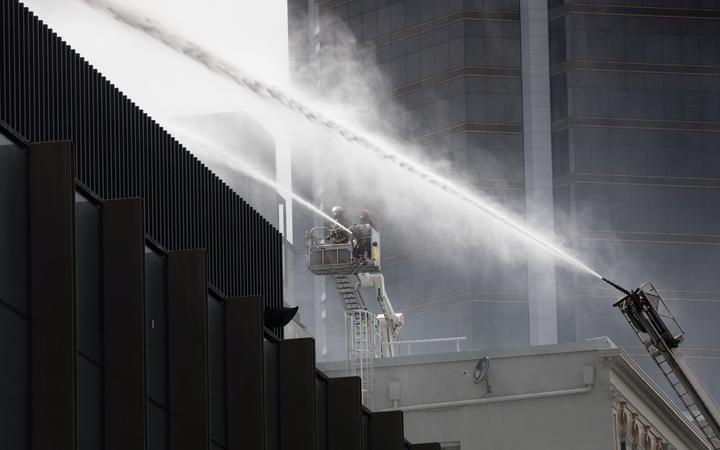 a lifter with fire
fighters using a hose to fight spray over a wall and another
with an mecanical hose