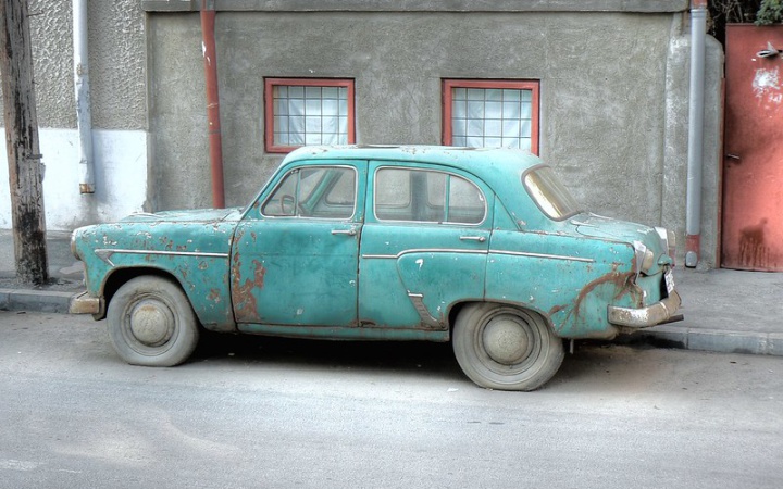 an old and very
worn out car parked on a street