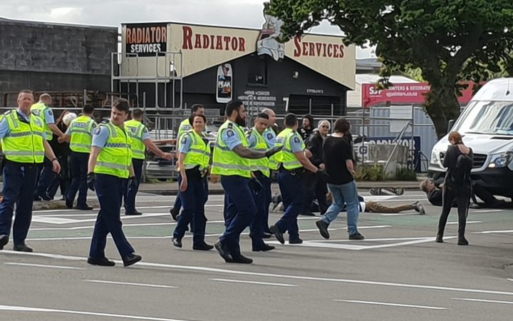 several protestors
on a road, mostly obscured by a forming line of police in
yellow vests