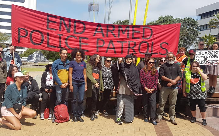 a group of people
under a banner reading: END ARMED POLICE PATROLS