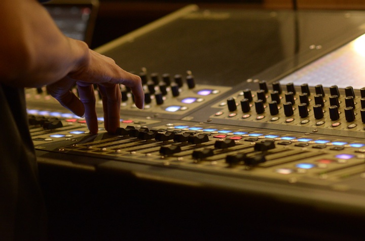 a sound desk with
someone's arm resting on it by the fingers