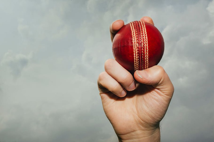 a hand holding a
cricket ball in the air in a bowling grip