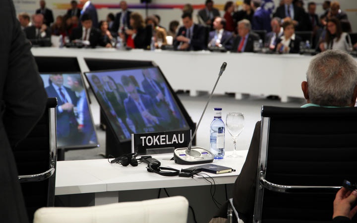 view from behind of
a desk labelled for Tokelau with a screen and microphone