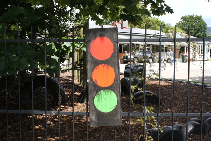 a painted picture
of a traffic light, attached to a school fence